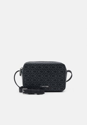 Bolso cruzado negro de Calvin Klein con cierre de cremallera, correa ajustable y patrón de monograma en tejido texturizado.