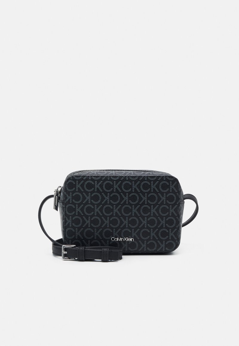 Crni Calvin Klein crossbody ručnik s zatvaranjem na zip, podesivim remenom i monogram uzorkom na taktilnoj tkanini.