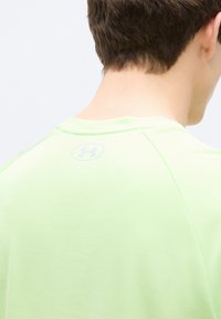 Αθλητική μπλούζα ανοιχτού πράσινου χρώματος με υφή. Διαθέτει στρογγυλή λαιμόκοψη και το λογότυπο της Under Armour ανάγλυφο στο πίσω μέρος.