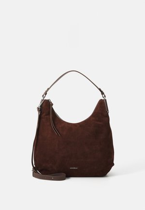 Dark brown suede handbag with a soft, rounded shape, a single shoulder strap, and a subtle zipper detail. Brand logo visible at the bottom.