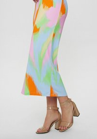 Rochie midi colorată cu modele abstracte în nuanțe de roz, albastru, verde și portocalie, asortată cu sandale cu toc bloc nude.
