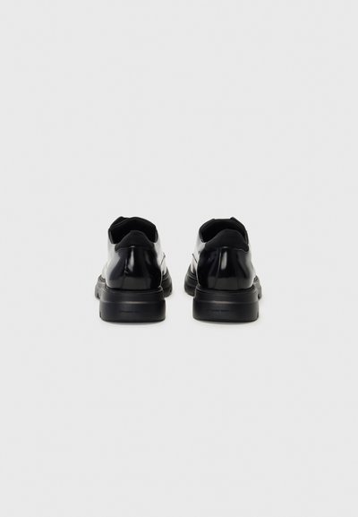 Black leather sneakers with a smooth finish, rounded toe, and a thick rubber sole. Minimalist design with no visible logos.