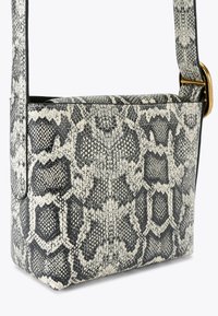 La borsa a spalla con stampa serpente presenta un design strutturato, in ecopelle testurizzata nera e bianca, con un accento in metallo dorato.
