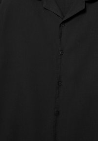 Czarna koszula zapinana na guziki z kołnierzem typu camp, z pięcioma widocznymi guzikami na środku przodu.