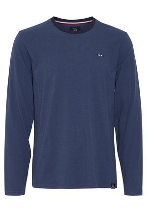 Tumesinine pikkade varrukatega särk, millel on ümmargune kaelus. Valmistatud pehmest puuvillast, sisaldab väikest logo ja triibulisi detaile kaelas. Lihtne disain.