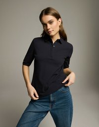 Granatowa koszulka polo z kołnierzykiem, krótkimi rękawami i dopasowanym krojem. W zestawieniu z jasnoniebieskimi dżinsami o klasycznym kroju i widocznym przeszyciu.