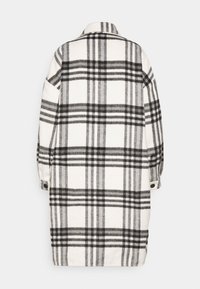 Abrigo de lana a cuadros en negro, blanco y gris; cuenta con un cuello, puños abotonados y un corte holgado con una silueta alargada.