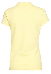 Takapuolet näkymä yksinkertaisesta lyhythihaisesta vaaleankeltaisesta polo-paidasta, jossa on pieni kaulus.