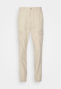 Pantaloni cargo beige con vita elastica, cordoncino, due tasche laterali e polsini elastici. Realizzati in un tessuto leggero con una superficie liscia.