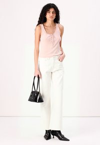 Light pink ribbed tank top with a buttoned placket, paired with white wide-leg trousers. Black handbag and pointed-toe black heels complete the look.