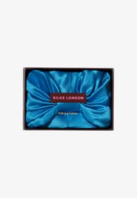 Tyrkise silketurban med en samlet design, presentert i en svart boks med en etikett som leser "SILKE LONDON" og "REN SILKE TURBAN."