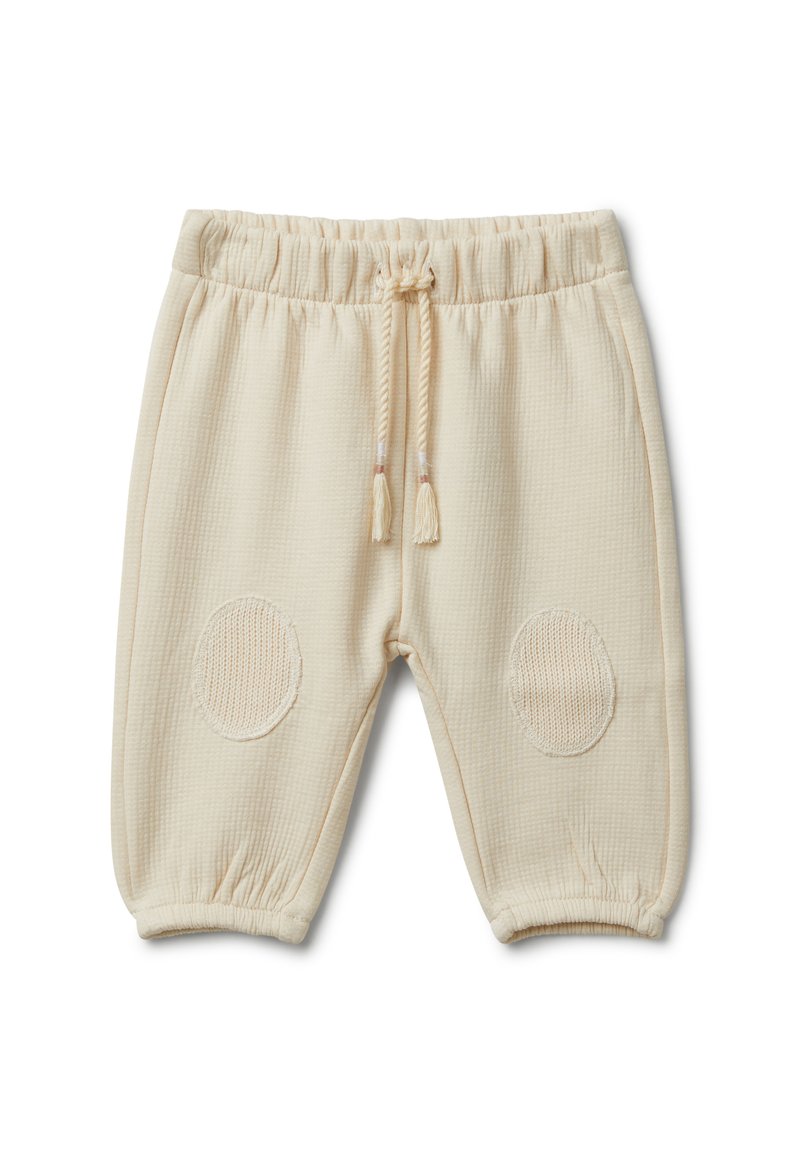 Beżowe bawełniane spodnie typu jogger z teksturowanym materiałem, elastycznym pasem i dzianinowymi naszywkami na kolanach. Zawierają regulowany sznurek.