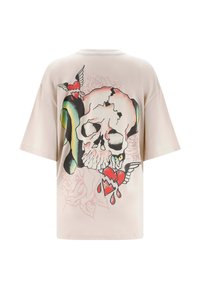 Cremefarvet oversized T-shirt med grafisk tryk, der viser et skull, røde hjerter og vinger. Kortærmet og med rund halsudskæring.