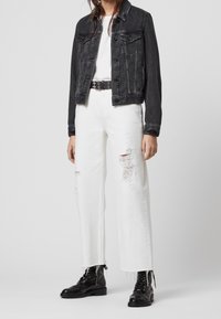 Černá džínová bunda, bílé oversized roztrhané džíny, černé vojenské boty a černý opasek se stříbrnými detaily. Jednoduchý, ležérní design.