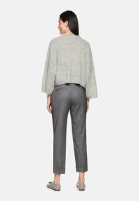 Light gray cropped sweater with dropped shoulders, paired with gray striped trousers and beige slip-on shoes, viewed from the back.