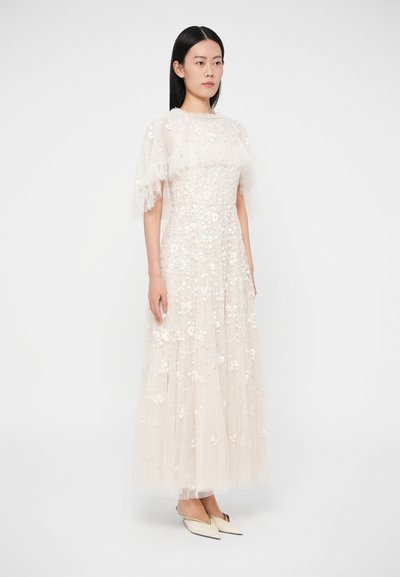 Μακρύ, ρέον φόρεμα από διάφανο, ανοιχτό μπεζ ύφασμα με διακοσμήσεις λουλουδιών. Κοντά μανίκια με βολάν και στενή κορυφή, με φούστα σε στρώσεις.