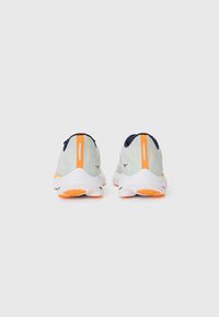 Chaussures de sport avec une tige en maille vert menthe clair, des accents bleu marine, des détails oranges et des semelles en caoutchouc texturé. Design épuré et moderne.