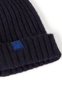 Berretto in maglia blu navy con texture a coste. Presenta una toppa blu con logo sul risvolto. Realizzato in morbida lana, garantendo calore.