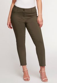 Olivově zelené strečové kalhoty s přiléhavým střihem, předními kapsami a zapínáním na knoflík, s manžetovými zipy a hladkou texturou.
