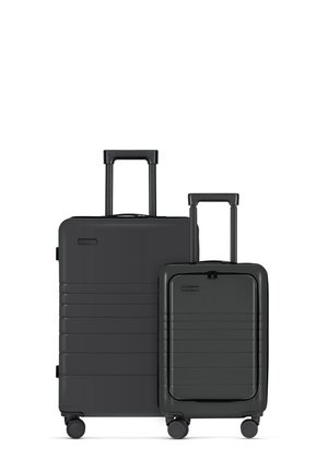 Two black hard-shell suitcases, one large and one small, with vertical grooves, telescopic handles, and four wheels each for easy mobility.