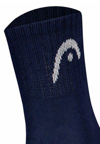 Mörkblå strumpa med ribbat mönster, prydd med en vit vågdesign vid kanten. Materialet verkar mjukt och elastiskt. Närbild.