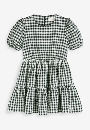 Czarna i biała sukienka w kratę gingham z krótkimi bufkami, okrągłym dekoltem, zamkiem błyskawicznym z tyłu oraz falbanami na stopniowanym dole. Materiał z mieszanki bawełny.