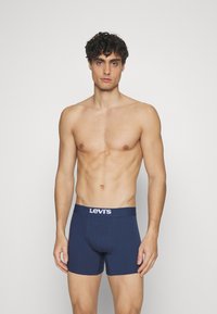 Dunkelblaue Baumwoll-Boxershorts mit einem weißen Levi's-Logo am elastischen Bund, in enganliegendem Design und mittlerer Oberschenkellänge.