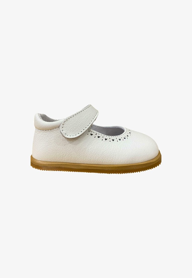 Zapato de cuero blanco con punta redondeada, correa de velcro ajustable y detalles decorativos perforados. Suela de goma con agarre texturizado.