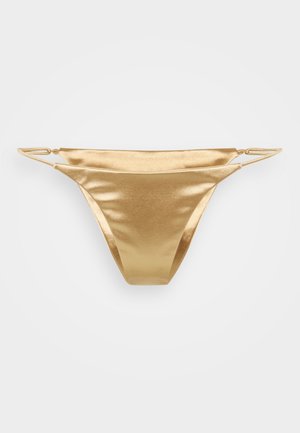 Bas de bikini doré avec une texture lisse et brillante. Présente un design minimaliste avec de fines bretelles et une ouverture de jambe haute.