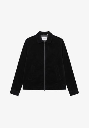 Svart corduroyjacka med krage, framdragkedja och två sidofickor. Har ett strukturerat tyg och kontrasterande manschetter.