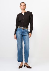 Czarny dzianinowy kardigan z guzikami, niebieskie jeansy o prostym kroju oraz brązowe czółenka na szpilce. Pasek w panterkę dodaje detalu.