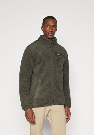 Green fleece jacket with high collar, zip front, side pockets, and logo patch on the chest. Soft texture and relaxed fit.
