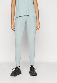 Αθλητικό κολάν σε ανοιχτό γαλάζιο χρώμα από ελαστικό ύφασμα, με παραδοσιακή στενή εφαρμογή και διακριτική λεπτομέρεια λογότυπου. Συνδυάζεται με μαύρα αθλητικά παπούτσια.