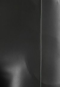 Black faux leather surface with a smooth texture, featuring a prominent vertical seam outlined in contrasting light stitching.