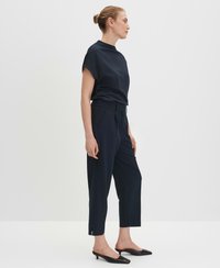 Dunkelblaue, kurz geschnittene Hose mit taillierter Passform, ausgestattet mit einem Gürtel, seitlichen Schlitzen und einer glatten Textur, kombiniert mit einem passenden Kurzarmoberteil.