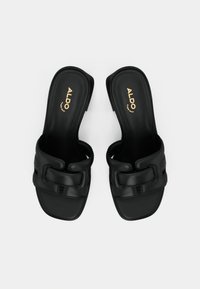 Schwarze Leder-Slipper mit quadratischen Zehen und breiten, gepolsterten Riemen, mit goldfarbenem ALDO-Logo auf den Innensohlen.