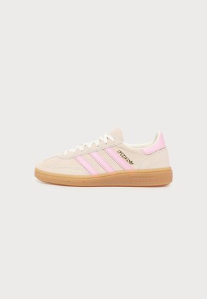 Pantof sport bej cu dungi roz, șireturi albe și talpă de cauciuc. Text auriu "Spezial" și logo Adidas pe lateral.