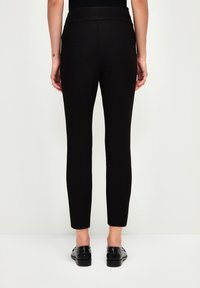 Zwarte slim-fit broeken met een hoge tailleband, gemaakt van soepel rekbaar materiaal. Het ontwerp heeft een strakke snit tot aan de enkels.