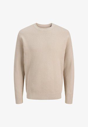 Koszula flanelowa w kratkę w odcieniach zieleni, beżu i ciemnej zieleni, z guzikami, noszona na prążkowanym beżowym swetrze, w połączeniu z czarnymi spodniami i ciemnymi butami.