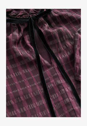 Permatomas bordo spalvos bliusonas su horizontaliais ir vertikaliais dryžiais, aksominiais akcentais, raukšlėtu apykakle ir V formos iškirpimu priekyje.