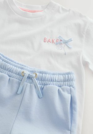 Valkoinen pitkähihainen paita, jossa vaaleanpunainen "BAKER"-teksti ja sininen rusetti, yhdistetty vaaleansinisiin, joustavaan vyötäröön ja nyörillä varustettuihin jogger-housuihin.