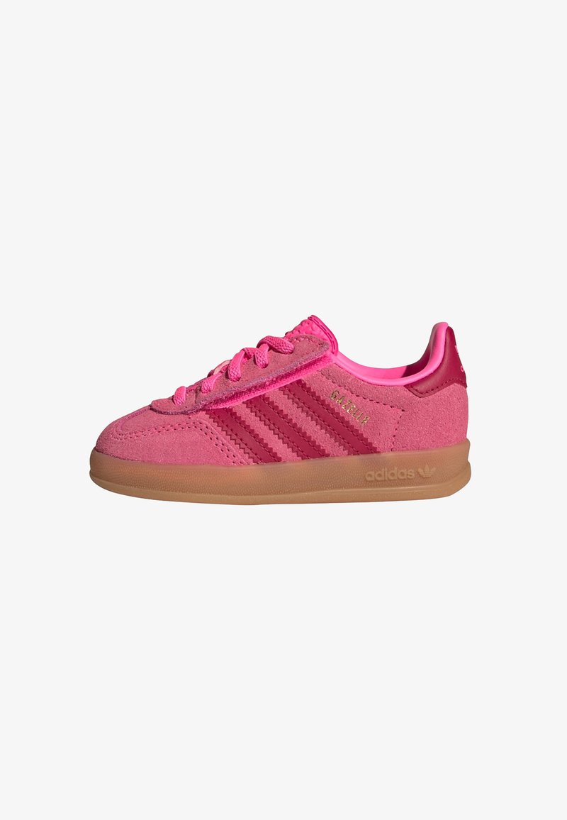 Baskets Adidas Gazelle roses avec dessus en daim, trois bandes rose plus foncé, semelle en gomme et marquage doré sur le côté sur fond blanc.