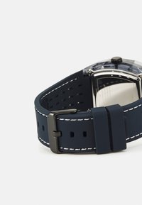 Navy Silikon-Uhrenarmband mit weißen Nähten, ausgestattet mit einer silberfarbenen Metallschließe und einem transparenten Uhrengehäuse an der Seite.