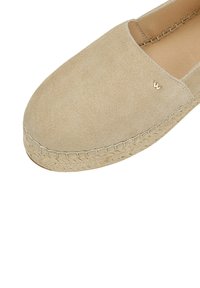 Beige suede espadrille with braided jute sole, slip-on style, and small metallic "W" logo on upper side near opening.