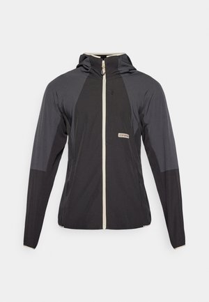 Veste légère noir et gris avec une fermeture éclair à l'avant, une capuche et un design de panneaux distinctifs. Présente un petit logo sur la zone de la poitrine.