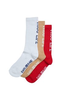 Tre par sockar: vita, bruna och röda. Varje par har en ribbad struktur med "THUG LIFE" och "KARL KANI" loggor i kontrasterande färger.