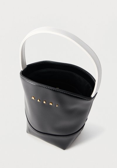 Μαύρη δερμάτινη τσάντα τύπου bucket με λευκή λαβή και χρυσά γράμματα λογοτύπου "MARNI" στο μπροστινό μέρος, εμφανιζόμενη ανοιχτή με ορατή την εσωτερική επένδυση.