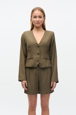 Olijfgroene, op maat gemaakte blazer met lange mouwen en knopen aan de voorkant, gecombineerd met bijpassende shorts, gemaakt van een gladde, lichtgewicht stof.