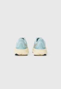 Lichtblauwe hardloopschoenen met een gestructureerde bovenkant en een crème tussenzool, met een oranje accentlogo en een opvallend ontworpen achterheel.