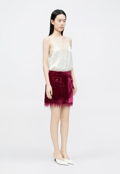 Siidist kampsun õhukeste pitsdetailidega, mida täiendatakse burgundi sametseelikuga, millel on kaks esimest taskut ja tuttidega ääris. Valged kontsakingad.